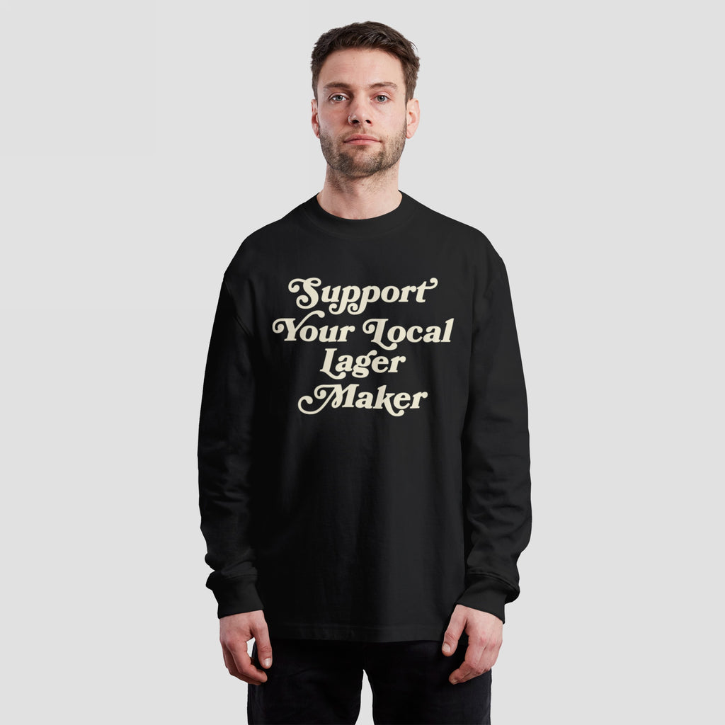 Person wearing a Support Your Local Lager Maker T-shirt, featuring cream-colored vintage lettering, advocating for local breweries. Ideal for expressing support and solidarity with independent lager producers.
