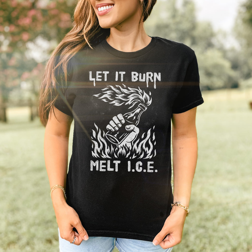 Woman wearing Let It Burn / Melt ICE Women's Baby Tee featuring Molotov cocktail graphic and text. The fitted black tee complements her casual jeans in a grassy, tree-lined setting.