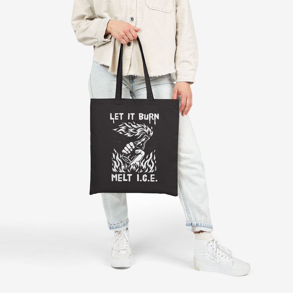The Let It Burn / Melt ICE Tote Bag features a bold graphic of a hand holding a flaming Molotov bottle, symbolizing anti-fascist sentiment, perfect for advocates of equality and immigrant rights.