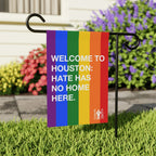 Custom Hate Has No Home Here Pride Garden Flag with rainbow stripes and bold white text, mounted on a black metal stand in a yard, promoting inclusivity and equality.