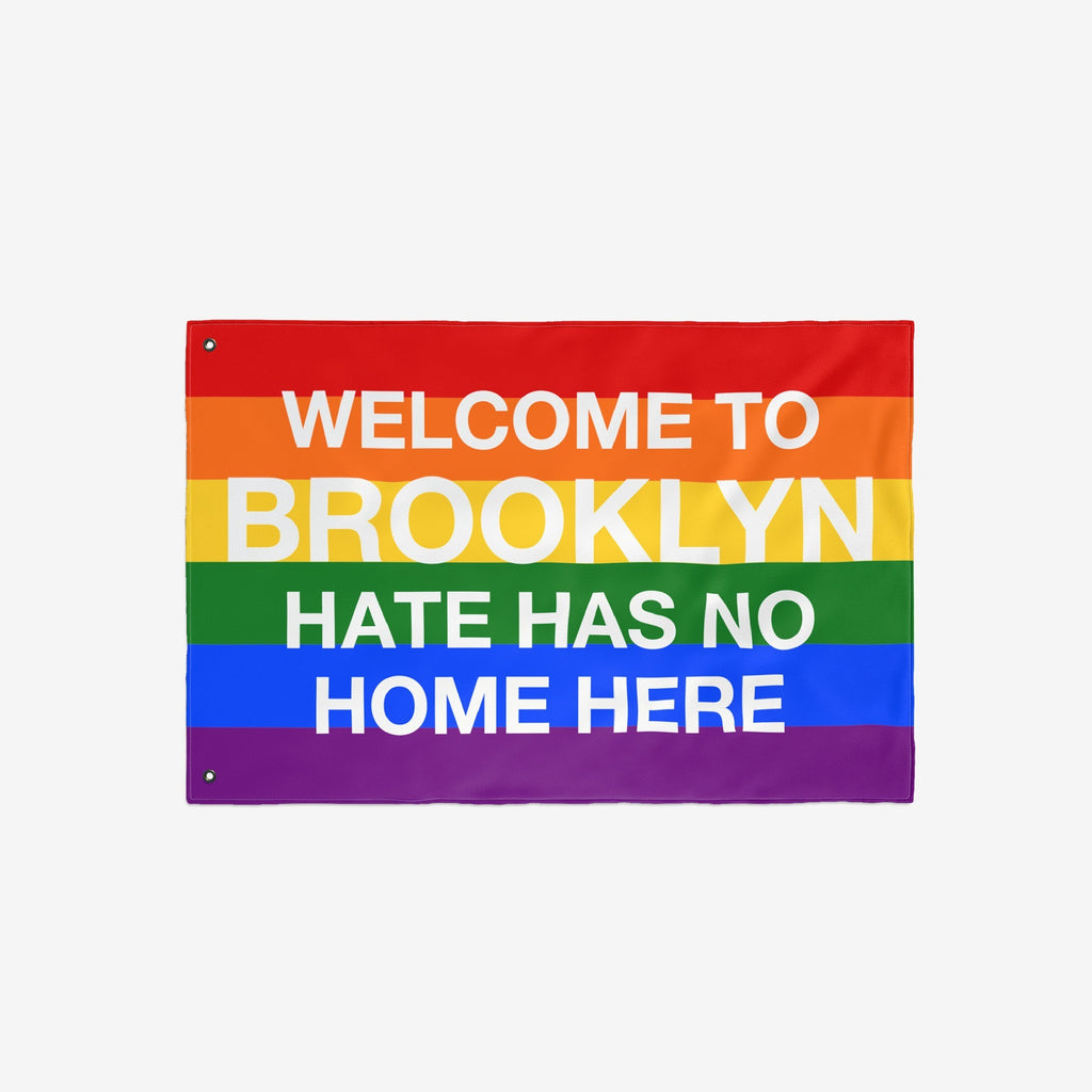Custom Hate Has No Home Here Pride Flag with bold white lettering on rainbow stripes, featuring metal grommets for hanging. Personalize with your city name to promote love, unity, and inclusion.