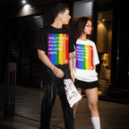 Two young adults wearing Custom Hate Has No Home Here Pride T-shirts with rainbow stripes and slogan, standing on an urban sidewalk, representing diversity and unity with casual street-style flair.