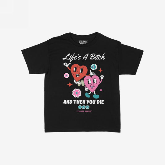 Life's A Bitch Women's Baby Tee features cartoon hearts dancing among flowers, paired with the phrase Life's A Bitch, And Then You Die, blending cute visuals with a candid message.