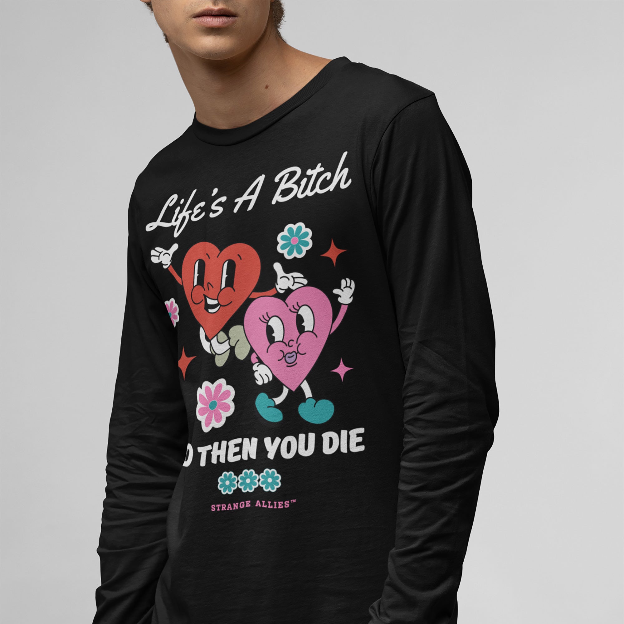 Person wearing the Life's A Bitch Shirt, featuring retro-cartoon hearts with Life’s A Bitch and then you die text, surrounded by flowers and stars, embodying unapologetic realism with a playful twist.
