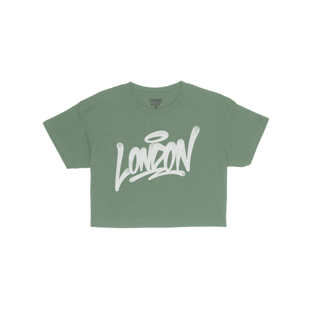 Bright green London Handstyle Women's Baby Tee features bold white graffiti-style script with a halo, embodying the store's c