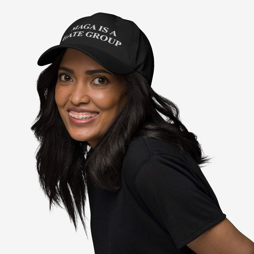 Young woman with braces wears a black MAGA Is A Hate Group Hat, advocating for equality and anti-fascism. The cap features white embroidered text, embodying a bold, progressive statement.