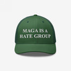 Forest-green trucker-style cap with MAGA IS A HATE GROUP embroidered in white on the front, featuring a mesh back and curved bill. Ideal for progressives and equality supporters.