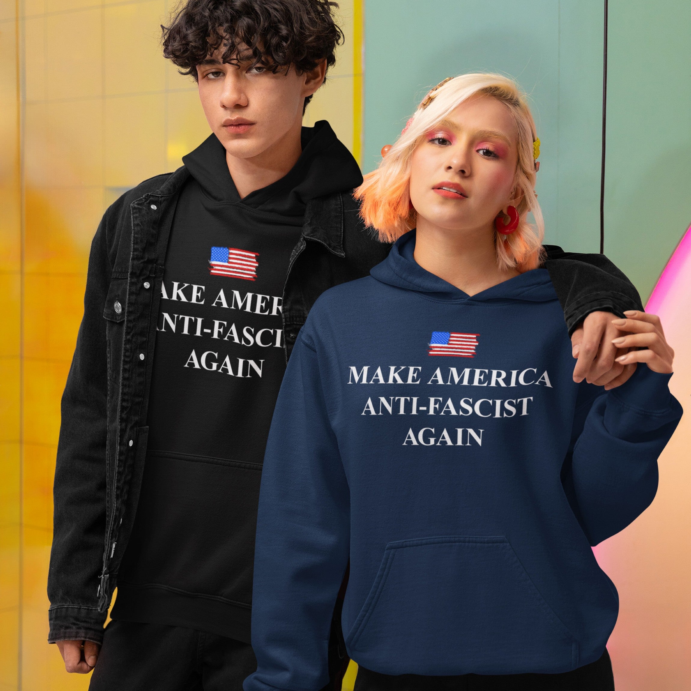 Two young adults model the Make America Anti-Fascist Again Hoodie & Sweatshirt, featuring a stylized U.S. flag and slogan, embodying anti-fascist and progressive values.
