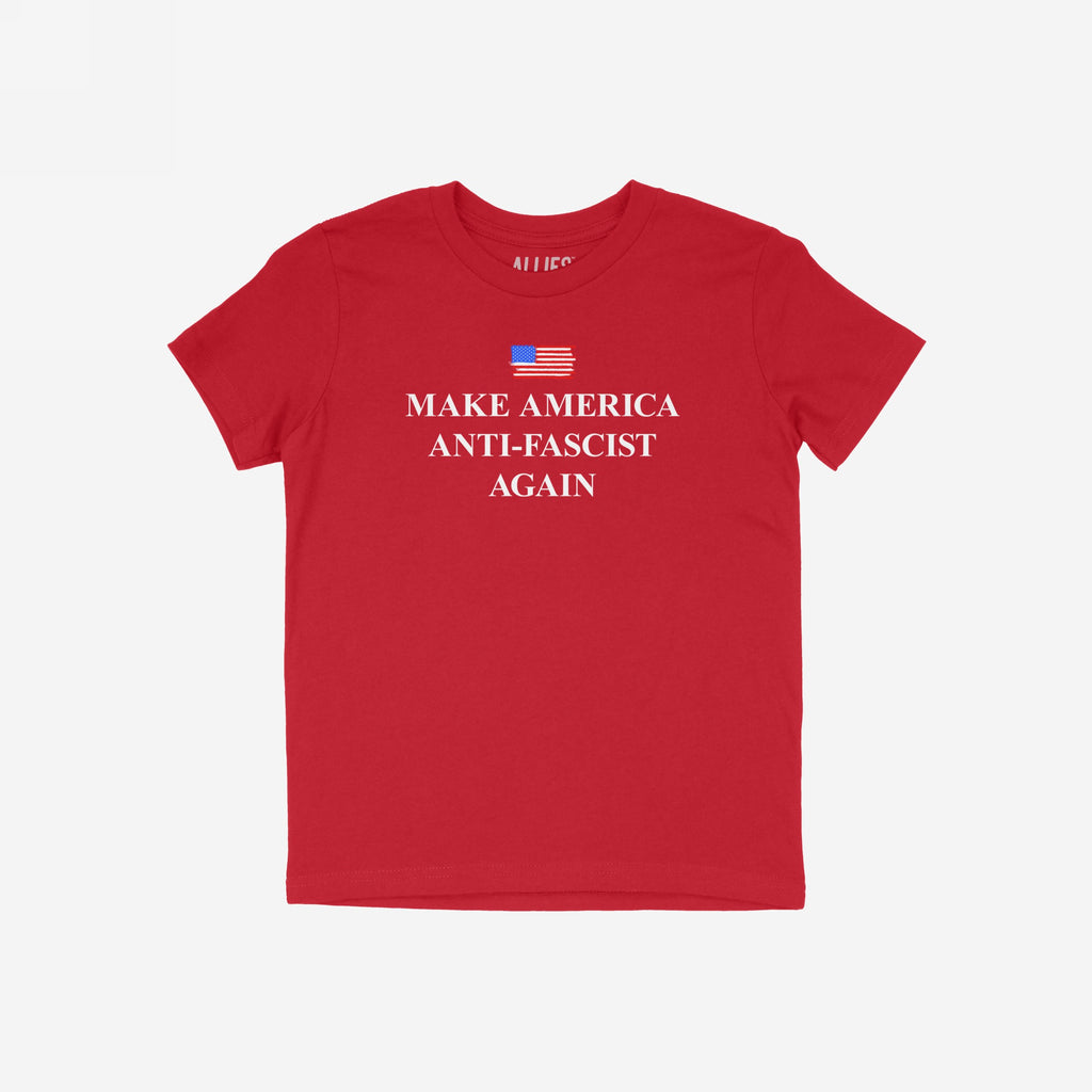 Plain red T-shirt titled Make America Anti-Fascist Again features a hand-sketched American flag graphic at chest level and bold serif slogan, conveying a strong anti-fascist message.
