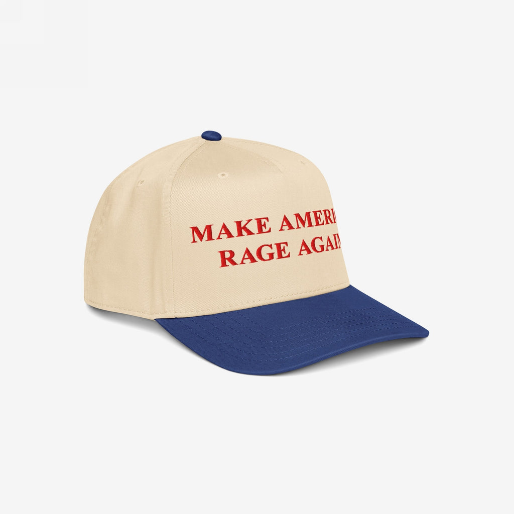 Make America Rage Again Hat, featuring a cream crown and royal blue bill, embroidered with bold red letters expressing anti-fascist sentiment. Ideal for showcasing values at protests and everyday outings.