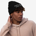 Young man in a light-beige hoodie wearing the Make America Rage Again knit beanie, featuring bold white text on the cuff, embodying anti-fascist sentiment and activist spirit.