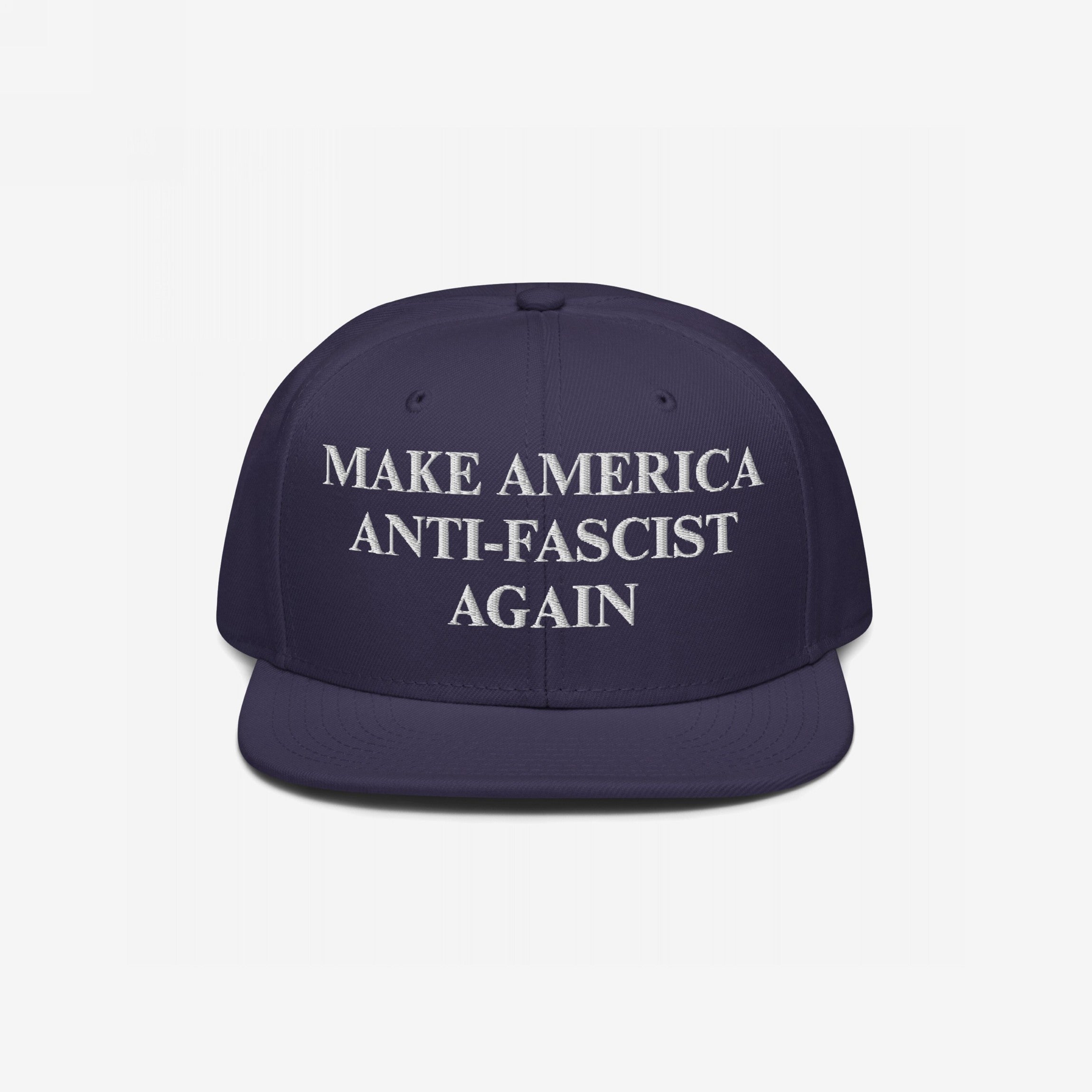 Dark navy-blue snapback hat with flat brim, featuring bold white embroidery reading “MAKE AMERICA ANTI-FASCIST AGAIN.” The Make America Anti-Fascist Again Hat boldly advocates for democracy and anti-authoritarianism.