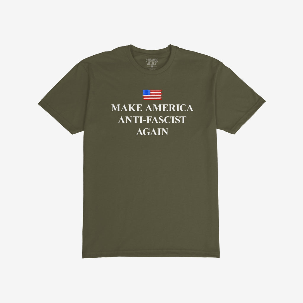 Make America Anti-Fascist Again T-shirt with a small U.S. flag and bold serif slogan, reflecting a stance against authoritarianism, showcasing the message above “STRANGE ALLIES” label inside the collar.