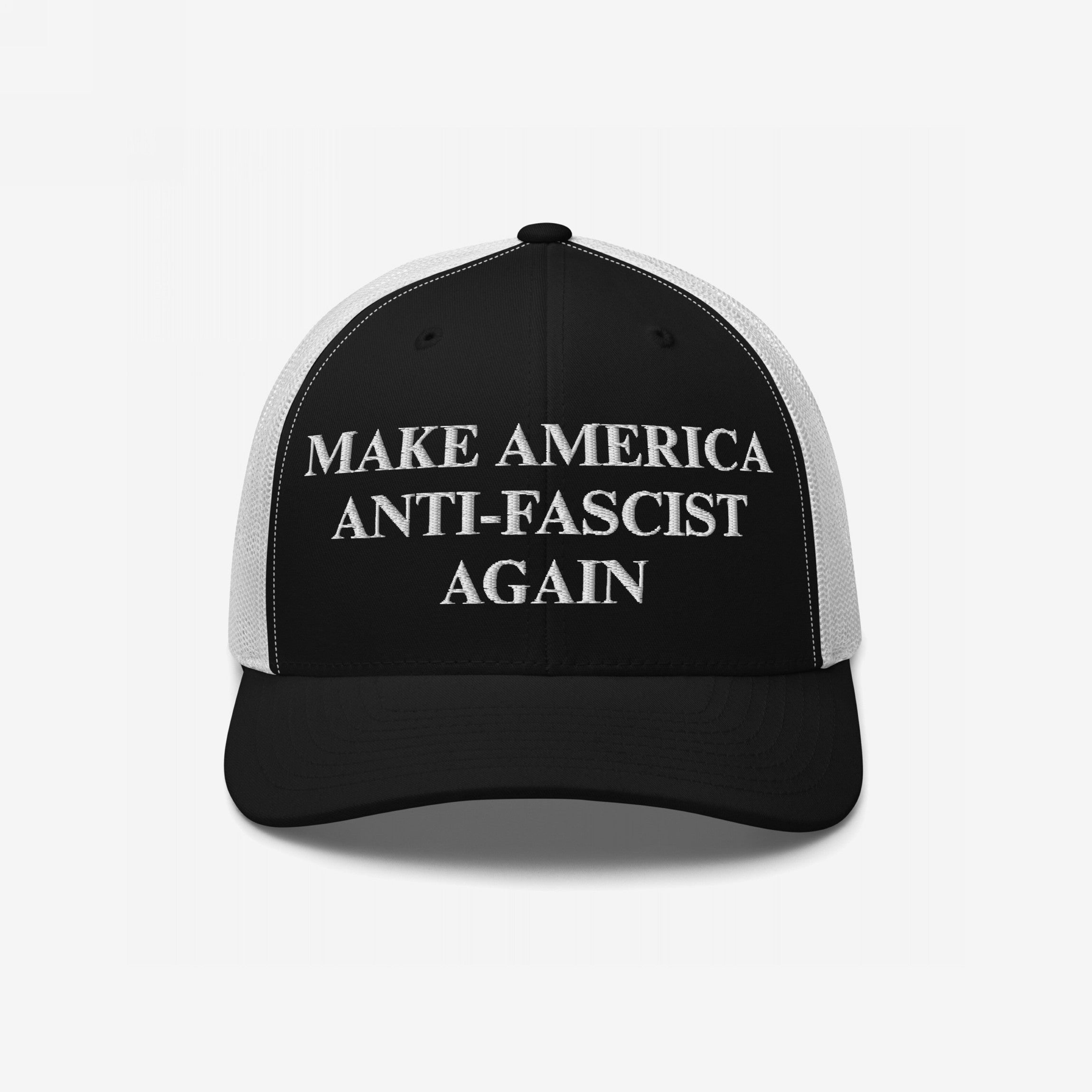 Make America Anti-Fascist Again Hat: Black-and-white trucker-style cap with white mesh, featuring bold white embroidered statement promoting anti-authoritarianism.