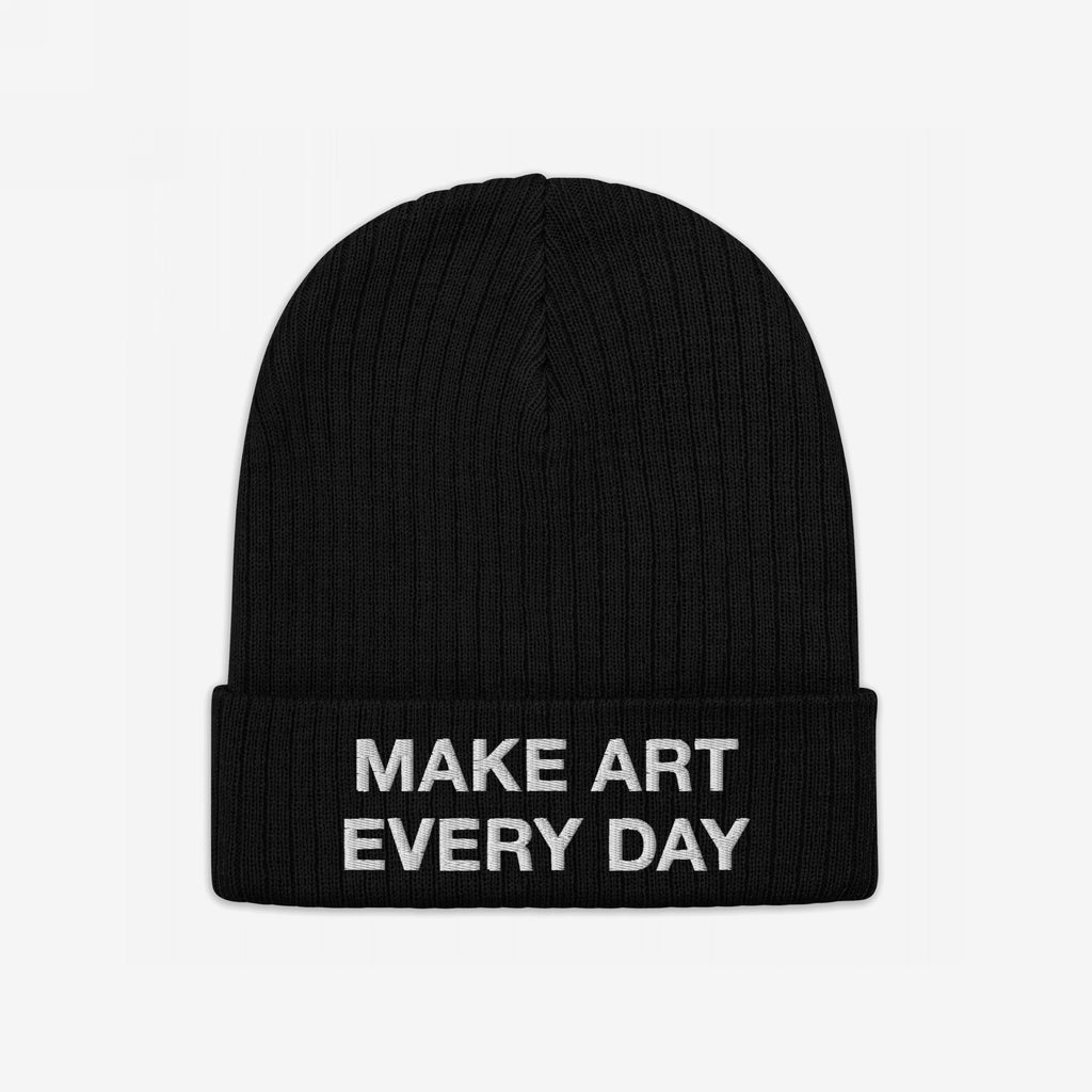 The Make Art Every Day Hat features a black rib-knit beanie with a folded cuff, embroidered in bold white letters, embodying creativity and individuality. Ideal for artists and visionaries.
