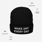 The Make Art Every Day Hat features a black cuffed knit beanie with a white embroidered slogan on the brim, narrow rib knit, double-layered recycled polyester, ideal for artists and creatives.