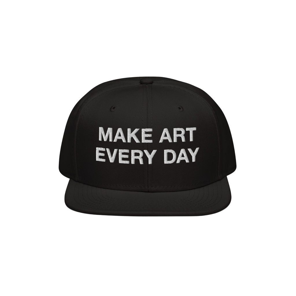 Black flat-brim snapback cap with “MAKE ART EVERY DAY” embroidered in bold white letters on the front. The back features 