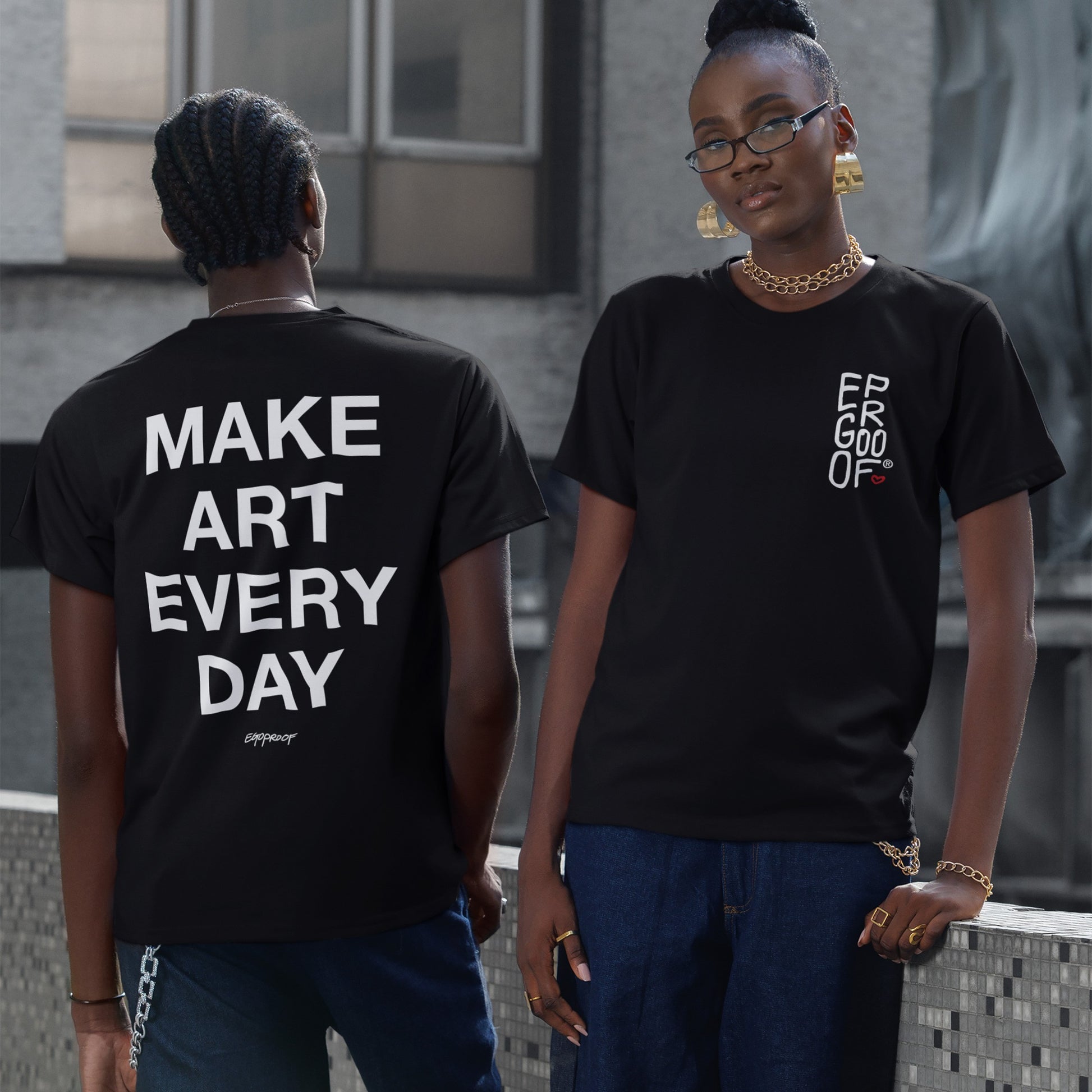 Two young adults showcase the Make Art Every Day T-shirt. One, facing backward, displays the bold back print, while the other, facing forward, highlights the understated front design, embodying creative street style.