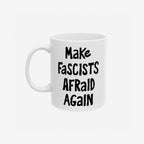 White ceramic mug with the slogan Make Fascists Afraid Again in bold black lettering. Features a standard C-handle, shiny finish, printed on both sides, and available in two sizes.