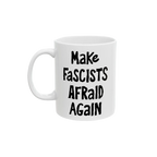 White ceramic mug with the slogan Make Fascists Afraid Again in bold black lettering. Features a standard C-handle, shiny finish, printed on both sides, and available in two sizes.