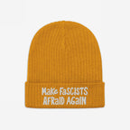 The Make Fascists Afraid Again Hat features a mustard-yellow knit with white embroidered slogan on its cuff, embodying defiance and supporting equality. Profits aid ACLU.