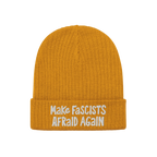 The Make Fascists Afraid Again Hat features a mustard-yellow knit with white embroidered slogan on its cuff, embodying defian