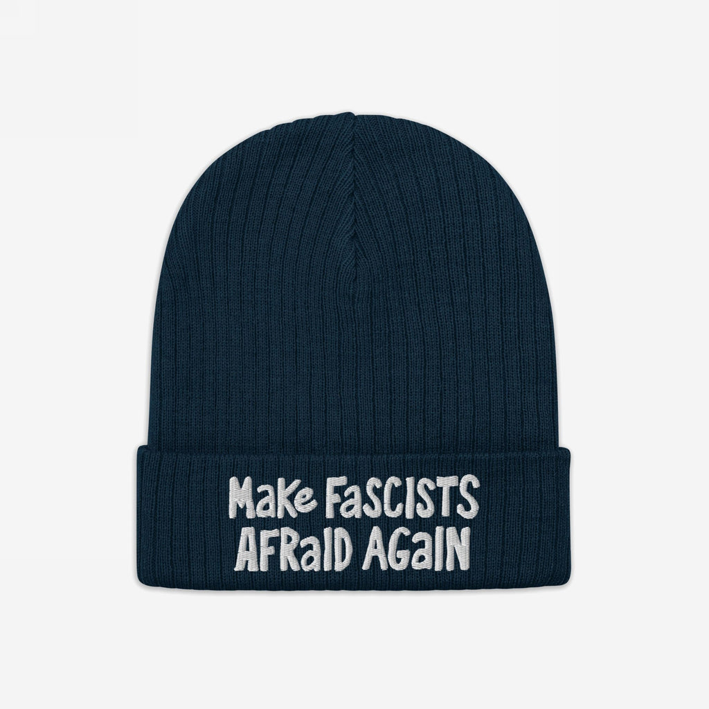 The Make Fascists Afraid Again hat features a navy knitted beanie with a folded cuff and bold white embroidered slogan, embodying everyday resistance and supporting equality. Proceeds benefit the ACLU.