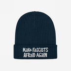The Make Fascists Afraid Again hat features a navy knitted beanie with a folded cuff and bold white embroidered slogan, embodying everyday resistance and supporting equality. Proceeds benefit the ACLU.