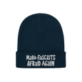The Make Fascists Afraid Again hat features a navy knitted beanie with a folded cuff and bold white embroidered slogan, embod