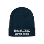 The Make Fascists Afraid Again hat features a navy knitted beanie with a folded cuff and bold white embroidered slogan, embod