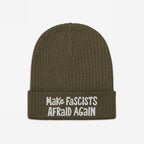 Make Fascists Afraid Again Hat: An olive-green, ribbed knit beanie with a folded cuff, featuring bold white embroidered slogan. Ideal for everyday resistance, embodying a stance against fascism with style and purpose.