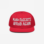 Red flat-brim cap with “Make Fascists Afraid Again” in white embroidery; embodies a bold, rebellious statement against fascism, ideal for protests or casual wear, supporting ACLU with each purchase.