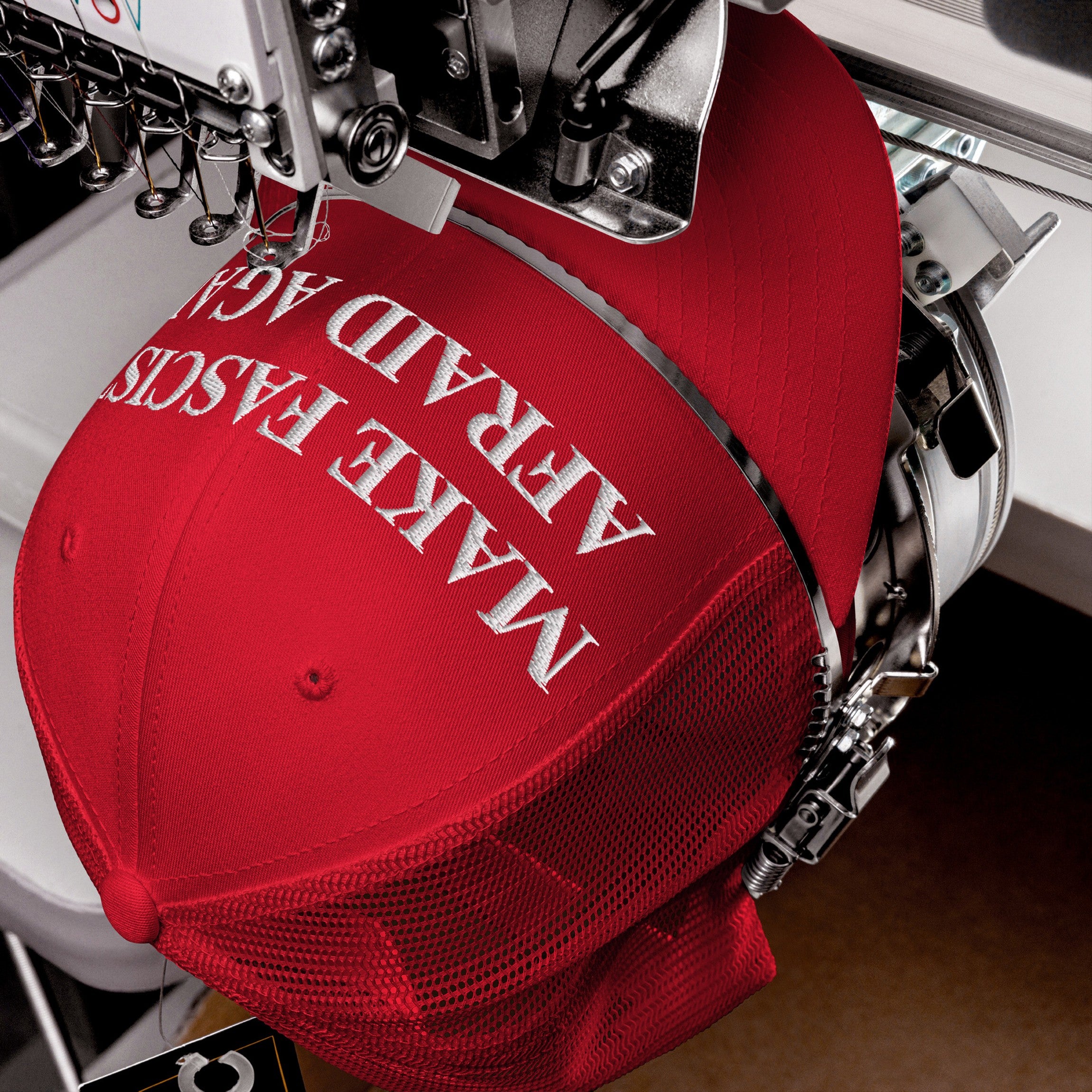 Red Make Fascists Afraid Again Classic Hat being embroidered on a machine, showcasing a bold anti-fascist slogan in white thread, perfect for activists seeking to make a statement.