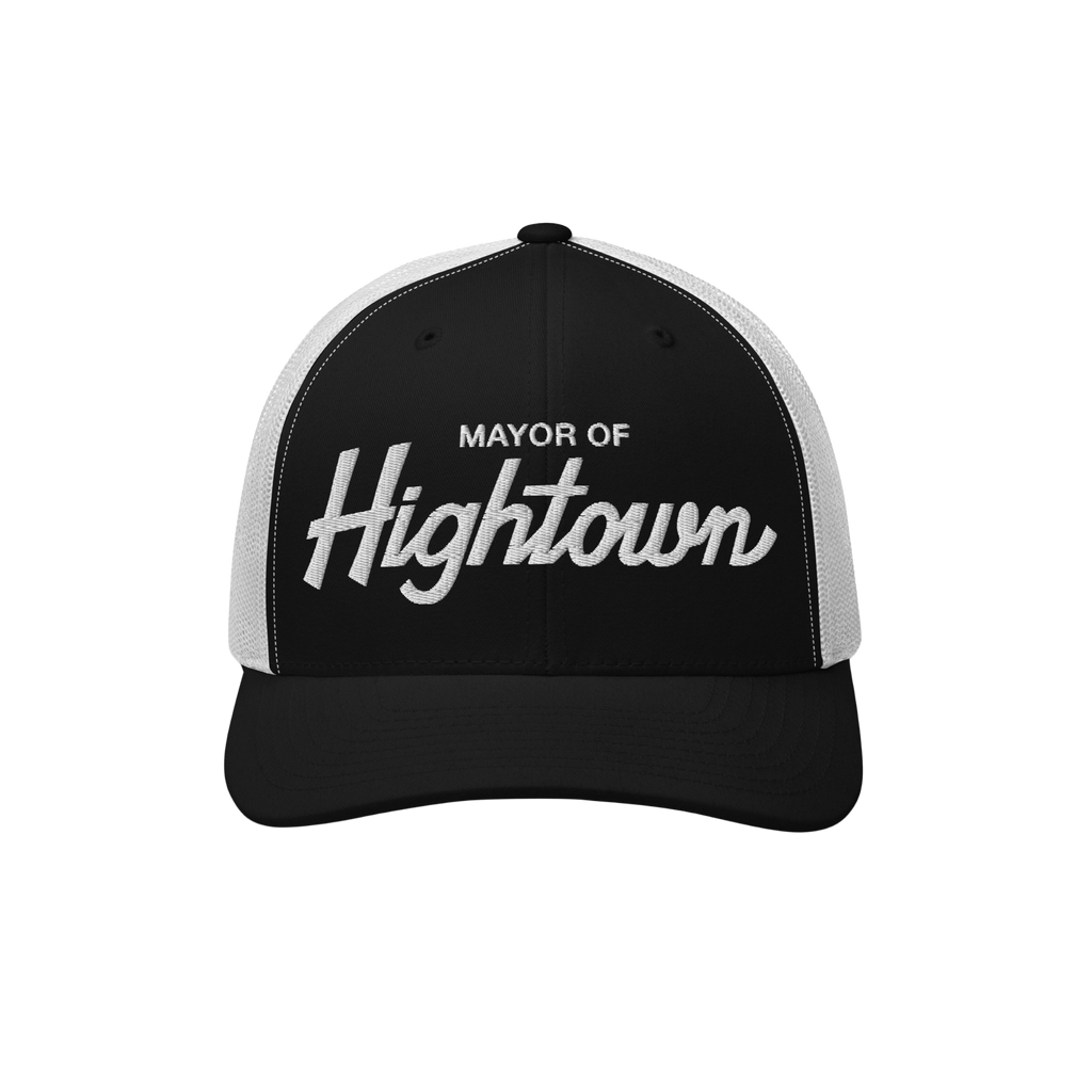 Trucker-style baseball cap with white mesh back, featuring MAYOR OF Hightown embroidered on the black front, reflecting a pla