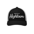 Trucker-style baseball cap with white mesh back, featuring MAYOR OF Hightown embroidered on the black front, reflecting a pla