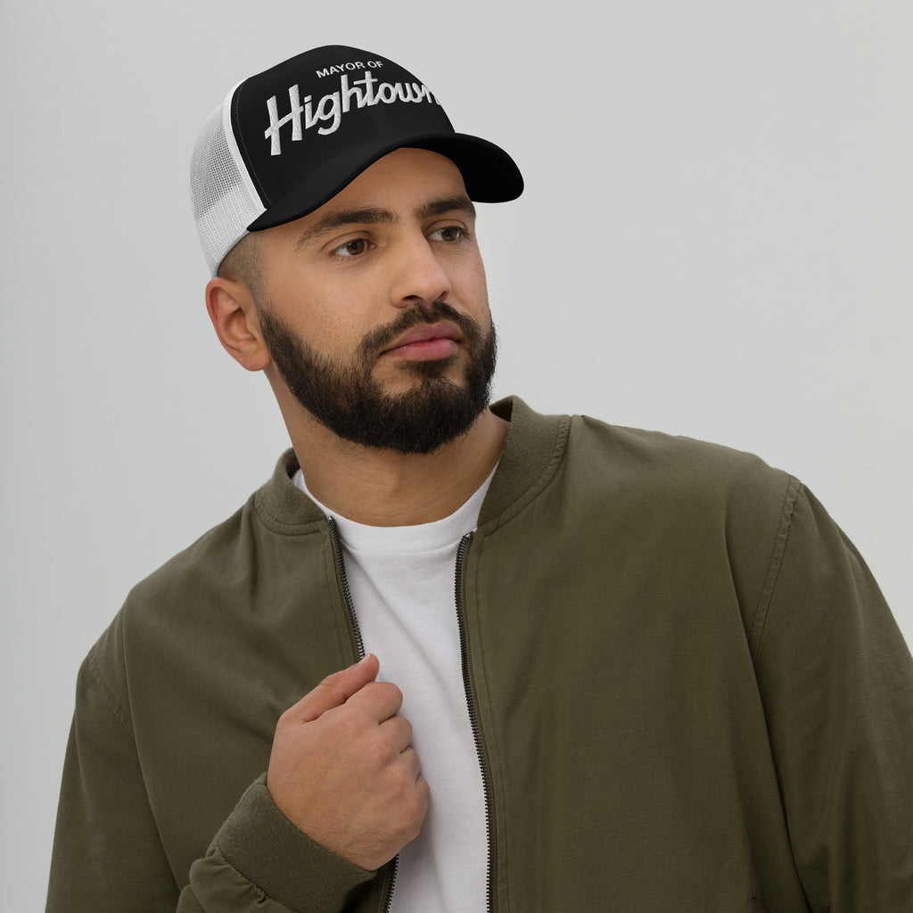 Young man wearing a Mayor of Hightown mesh baseball cap, embodying cannabis culture's playful spirit. Styled with an olive bomber jacket and white tee, reflecting a laid-back, bold attitude.