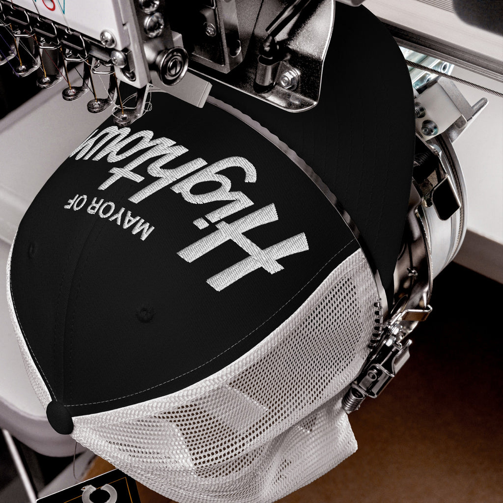 The Mayor Of Hightown Hat under embroidery, showcasing bold white letters on a black-and-white mesh cap, embodying cannabis culture's vibrant, carefree spirit and unapologetic attitude.