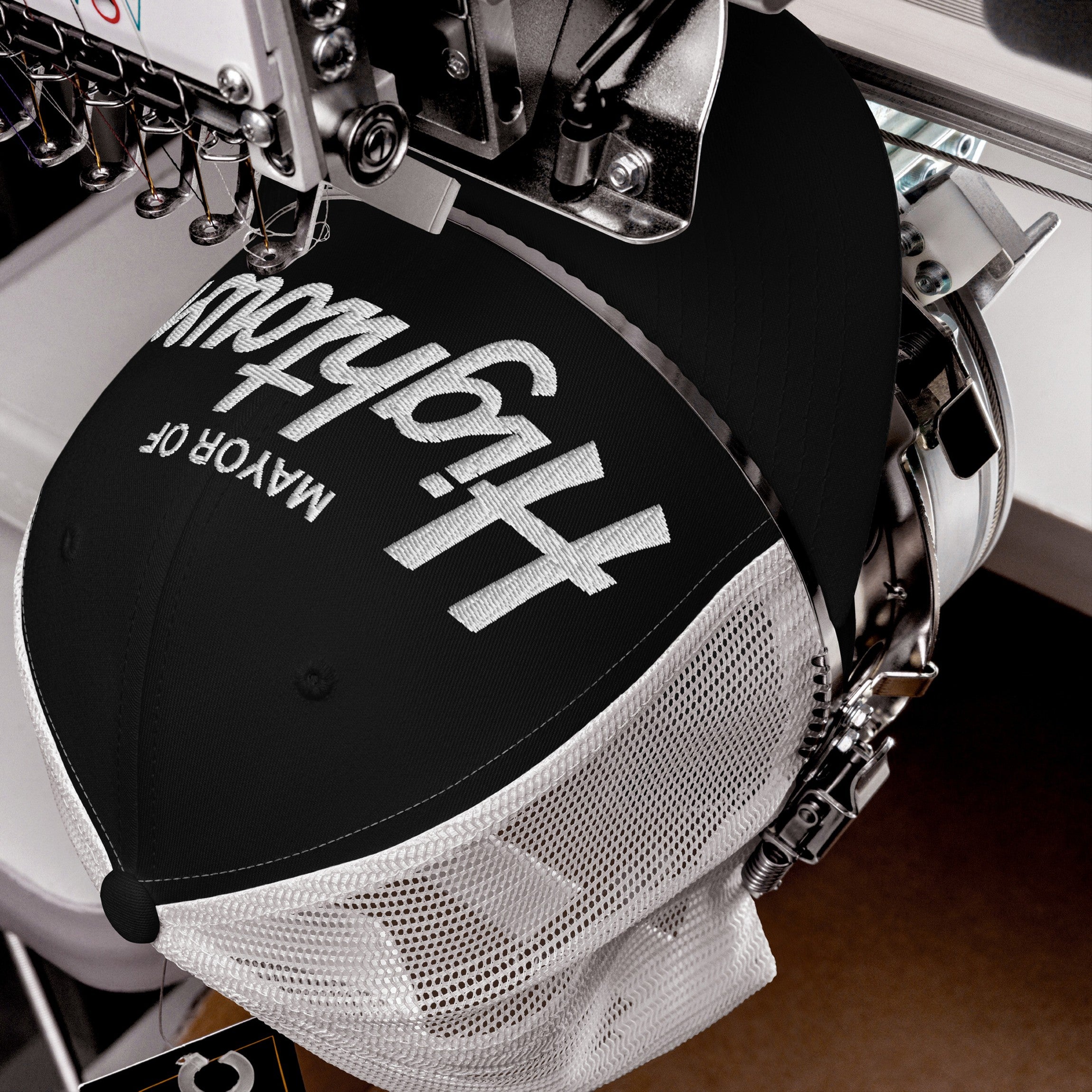 The Mayor Of Hightown Hat under embroidery, showcasing bold white letters on a black-and-white mesh cap, embodying cannabis culture's vibrant, carefree spirit and unapologetic attitude.