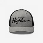 Two-tone trucker-style Mayor of Hightown Hat with light gray front and black mesh back, featuring bold embroidered lettering, embodying a playful, cannabis-inspired vibe for laid-back enthusiasts.