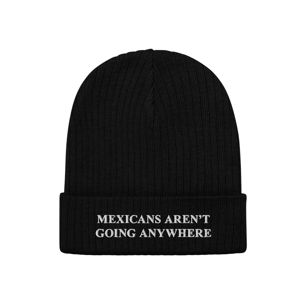 Black rib-knit beanie with bold white embroidered text on the cuff, reading “MEXICANS AREN’T GOING ANYWHERE,” represent