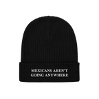 Black rib-knit beanie with bold white embroidered text on the cuff, reading “MEXICANS AREN’T GOING ANYWHERE,” represent