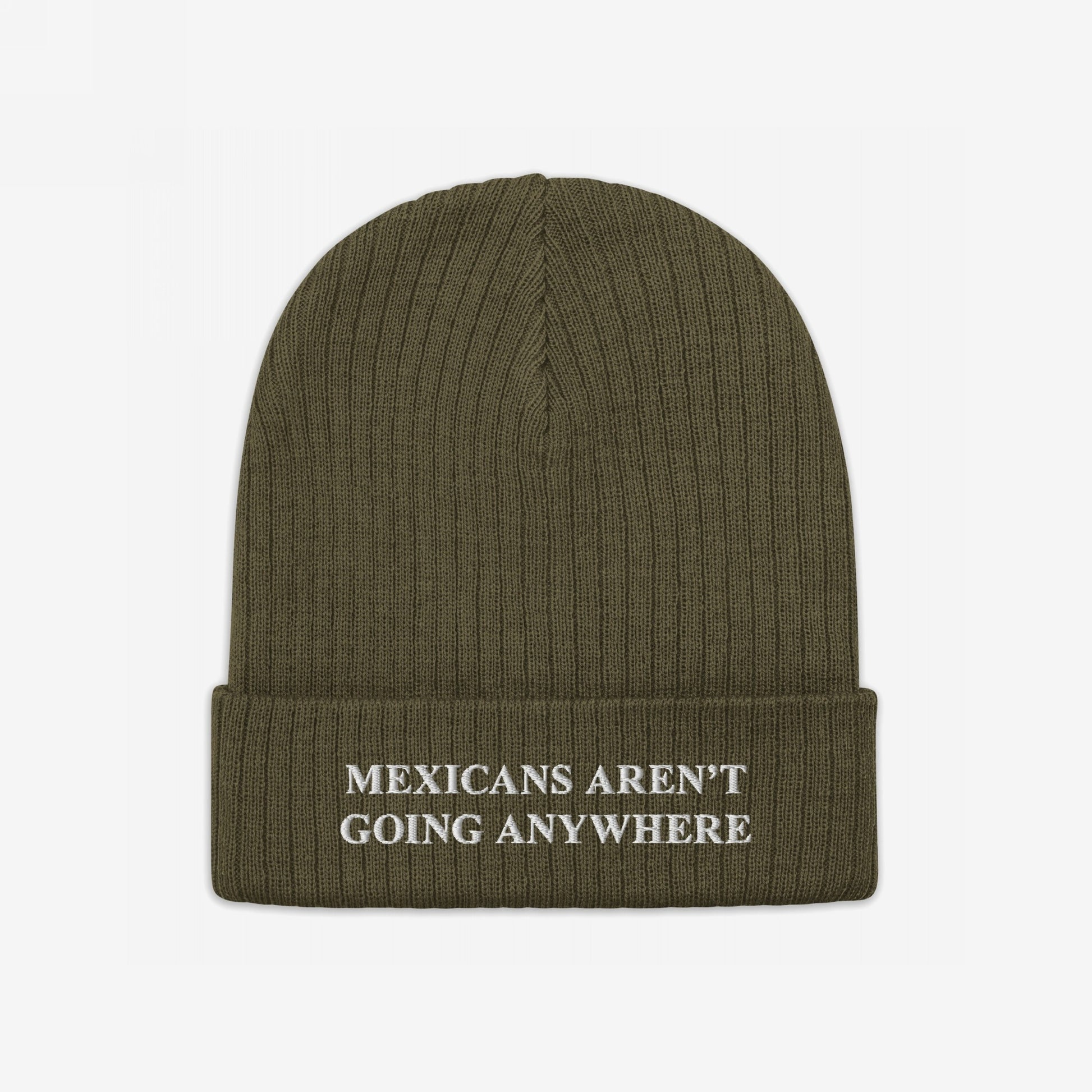 The Mexicans Aren’t Going Anywhere Hat features an olive-green rib-knit beanie with a folded cuff, embroidered with a bold, white message advocating pride and resilience against racism and anti-immigrant sentiments.