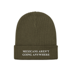 The Mexicans Aren’t Going Anywhere Hat features an olive-green rib-knit beanie with a folded cuff, embroidered with a bold,