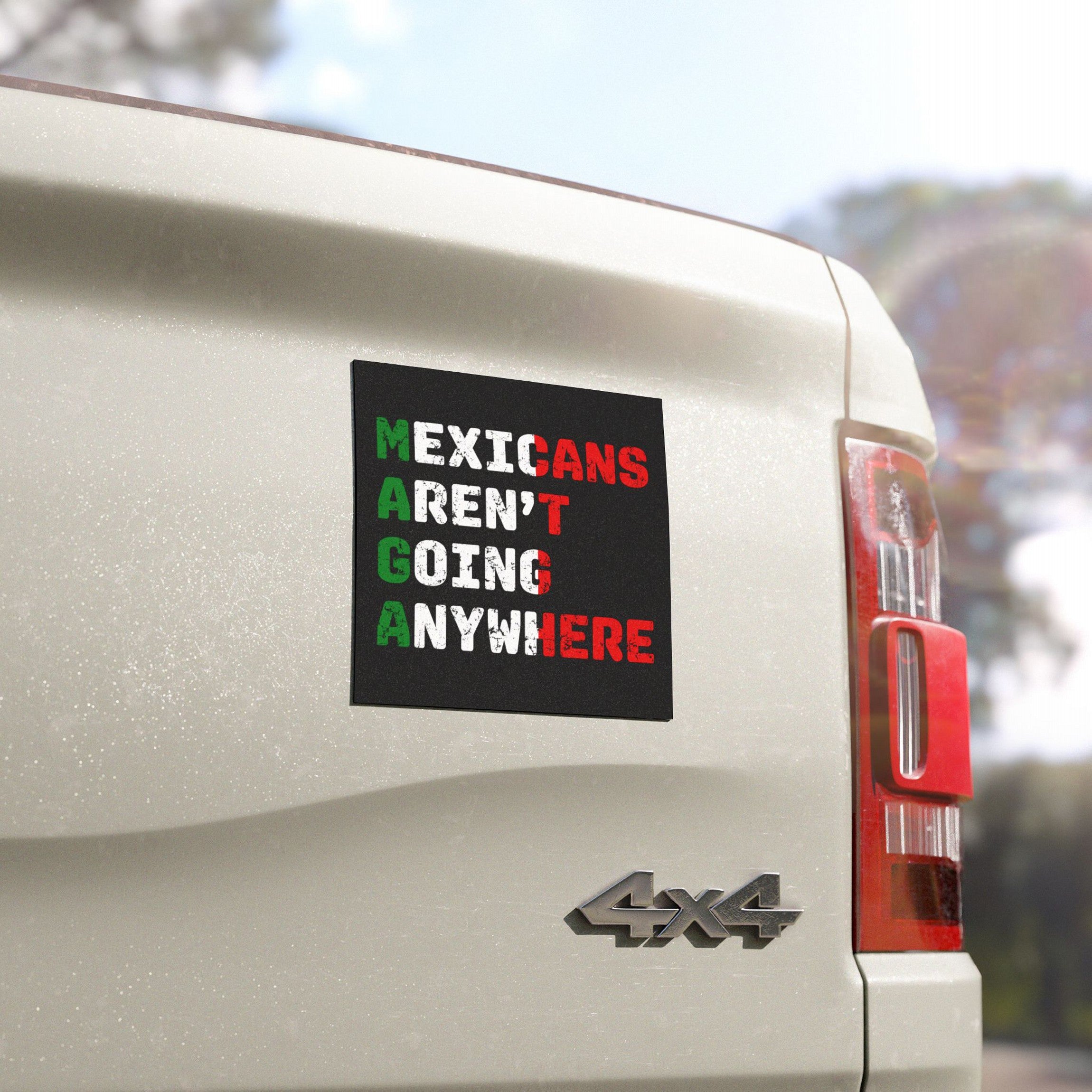 The Mexicans Aren't Going Anywhere Sticker & Magnet is displayed on a white 4x4 pickup truck tailgate, showcasing its bold design with a powerful message of resilience against xenophobia.