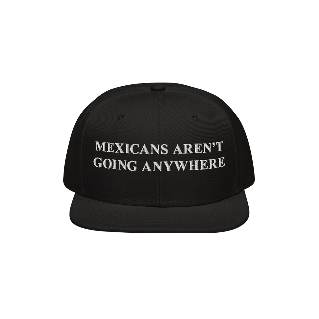 Black snapback hat featuring bold white embroidery reading “Mexicans Aren’t Going Anywhere,” symbolizing pride and resi