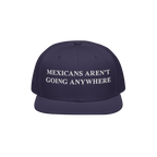 Navy snap-back cap with white embroidered Mexicans Aren’t Going Anywhere text, embodying pride and resistance against racis