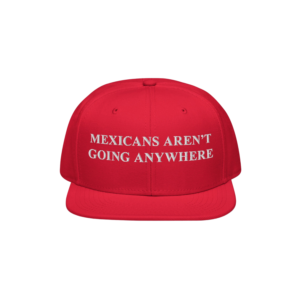 Red snap-back baseball cap with white embroidered text, “Mexicans Aren’t Going Anywhere,” symbolizing pride and resista