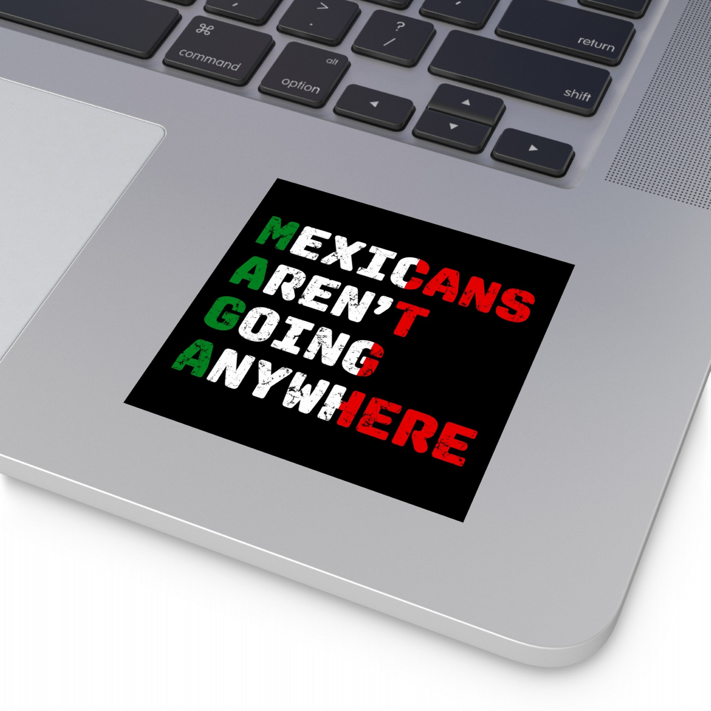 Mexicans Aren't Going Anywhere Sticker & Magnet on a silver laptop, displaying bold distressed-style lettering, a proud statement against xenophobia with Mexican flag colors. Ideal for expressing cultural resilience and identity.