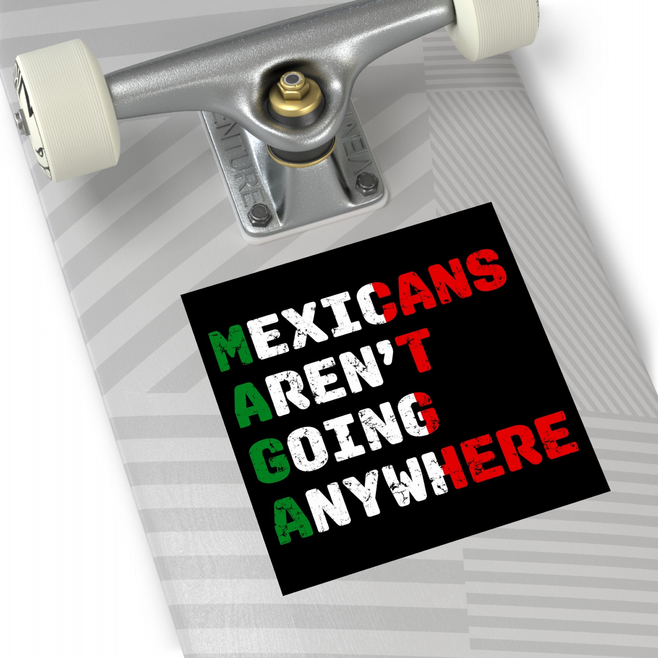 Mexicans Aren't Going Anywhere Sticker & Magnet on skateboard underside, showcasing a bold, anti-xenophobia message with distressed-style lettering, embodying resilience and cultural pride against anti-immigrant sentiments.