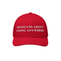 The Mexicans Aren’t Going Anywhere Hat showcases a bold statement with white embroidery on a red trucker cap, featuring a m